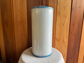 A white cylindrical Davey filter cartridge for hot tubs, displayed against a wooden background.